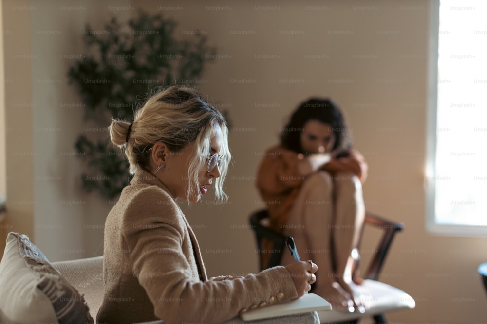 una donna seduta su un divano che scrive su un pezzo di carta