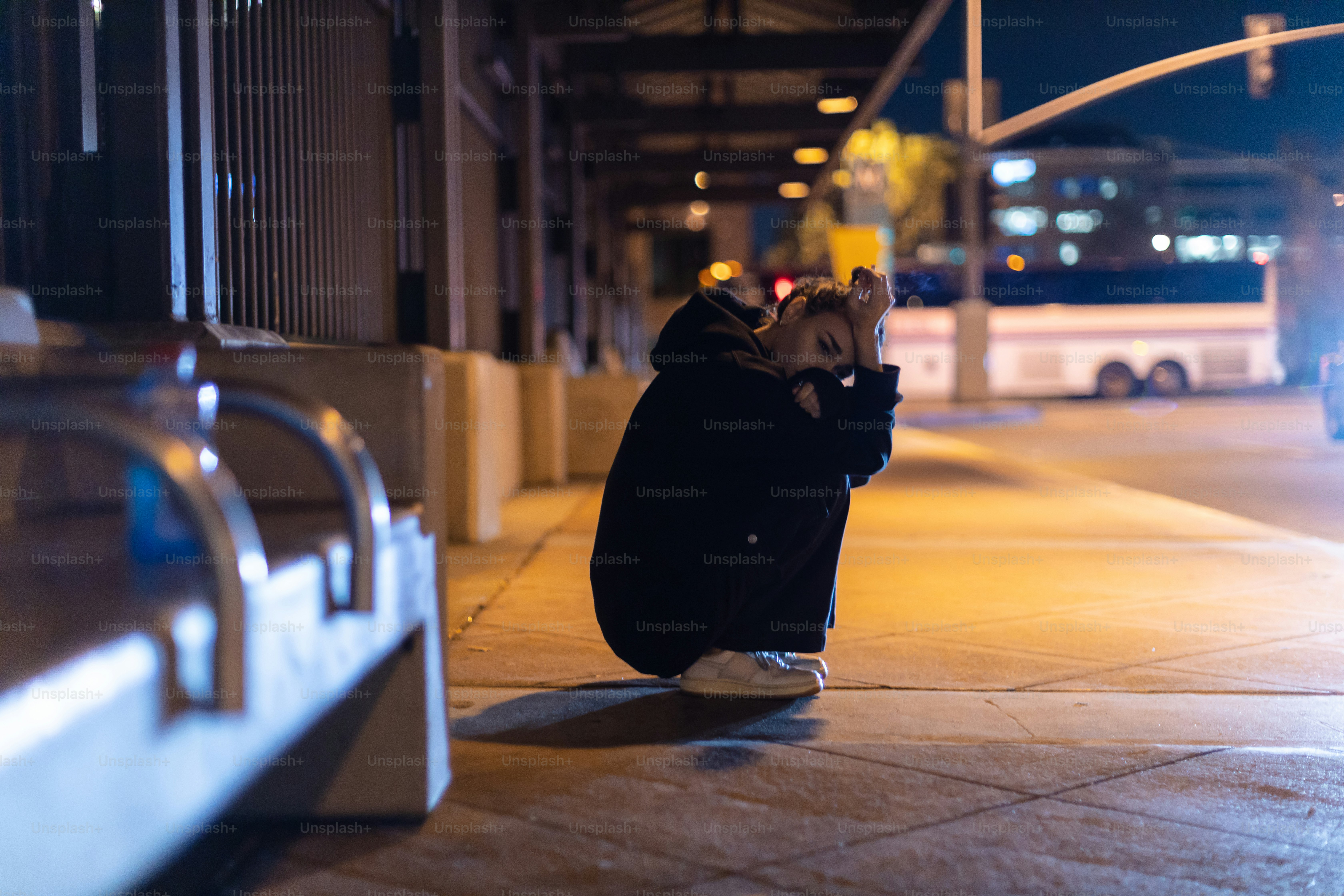 a person sitting on the ground in front of a bus