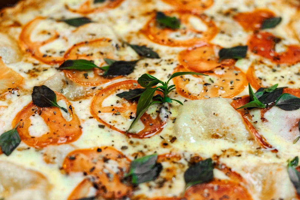 Un primer plano de una pizza con tomates y albahaca