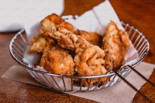 a basket filled with fried food on top of a wooden table