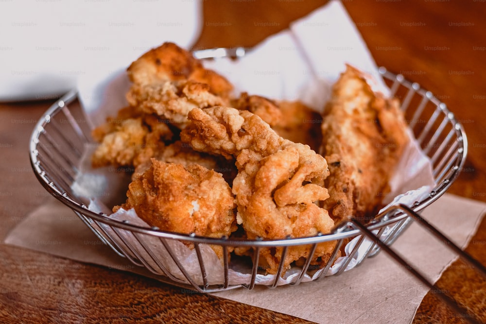 a basket filled with fried food on top of a wooden table