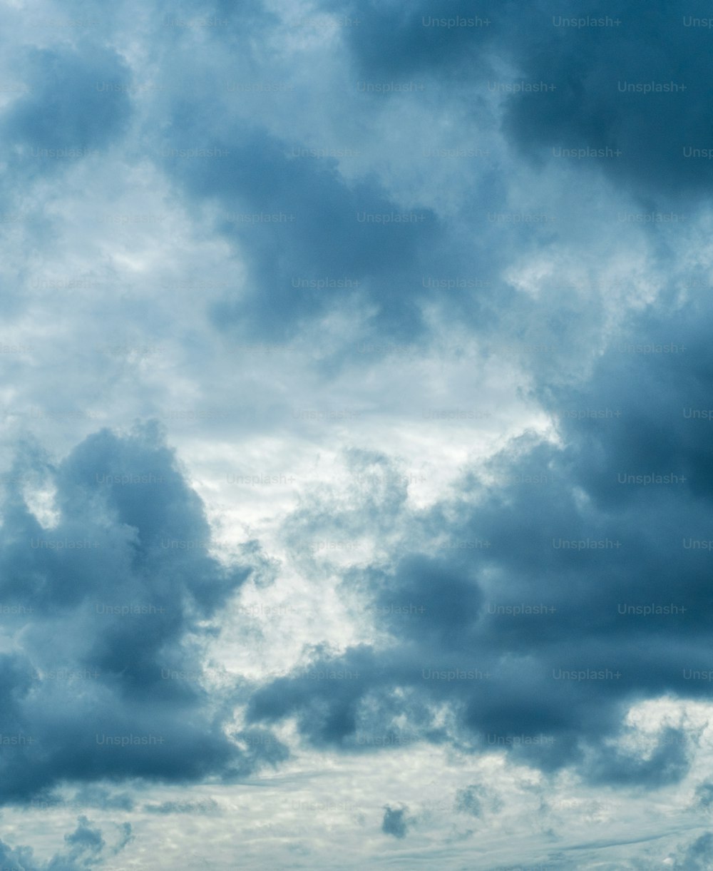 a plane flying through a cloudy blue sky