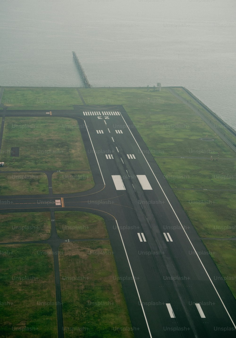 an aerial view of an airport runway with a body of water in the background