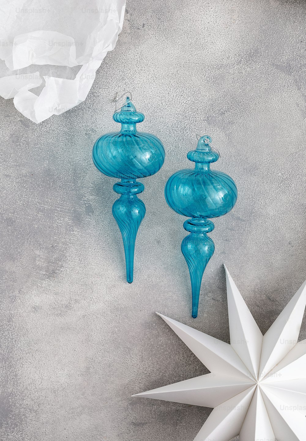dois ornamentos de vidro azul sentados em cima de uma mesa