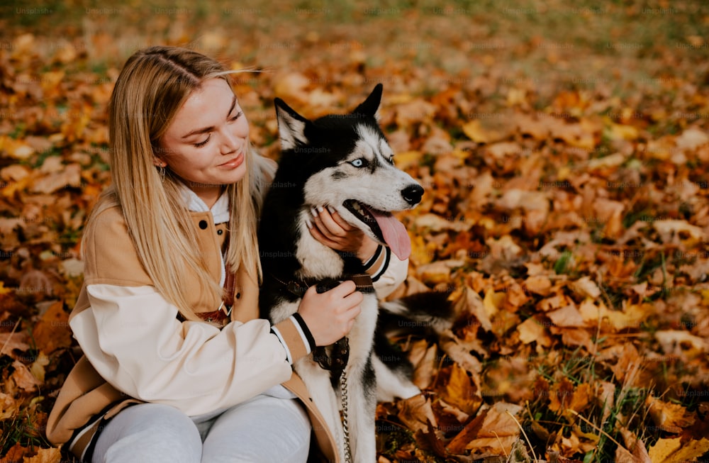 a woman holding a husky dog in a field of leaves
