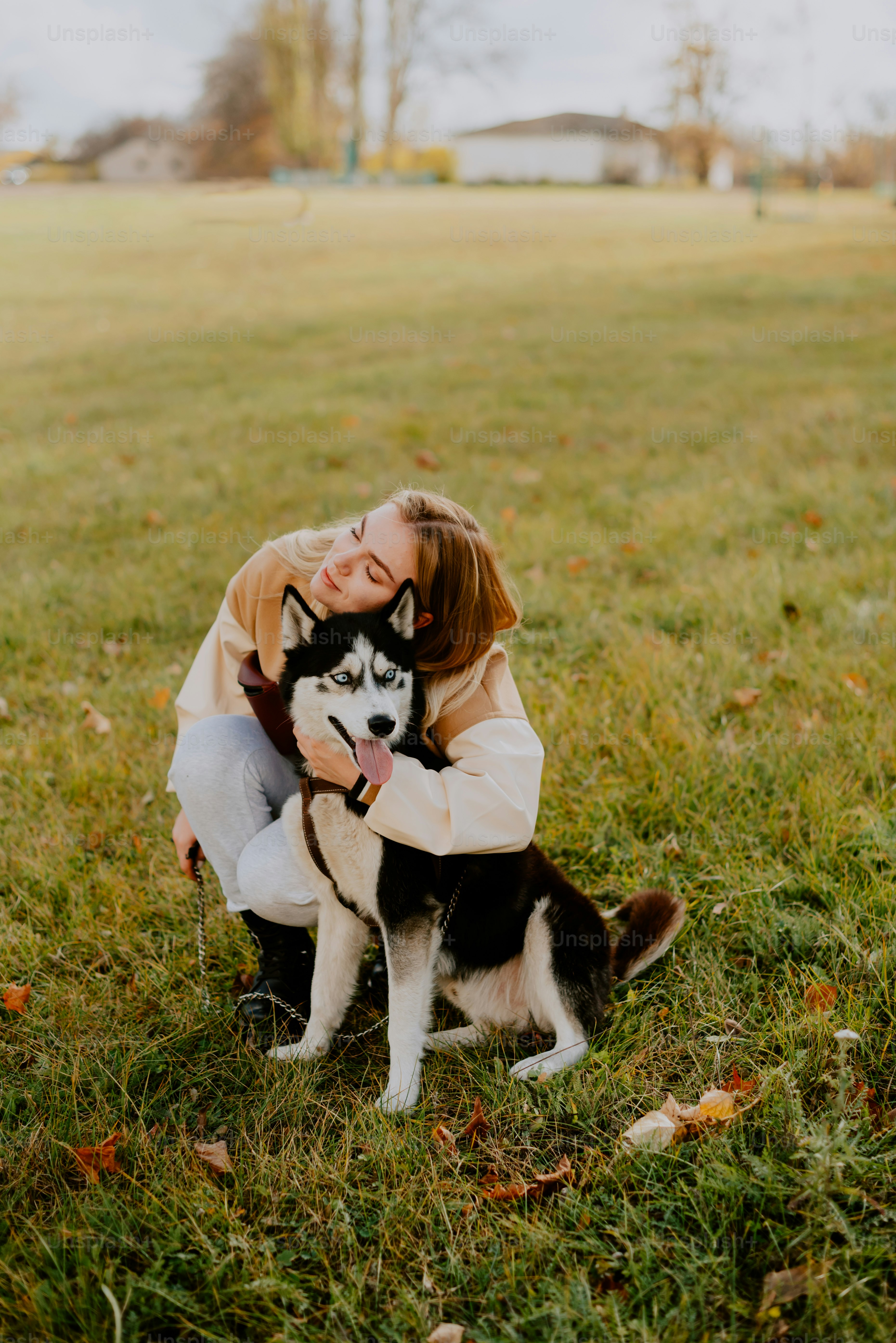 a woman hugging a husky dog in a field