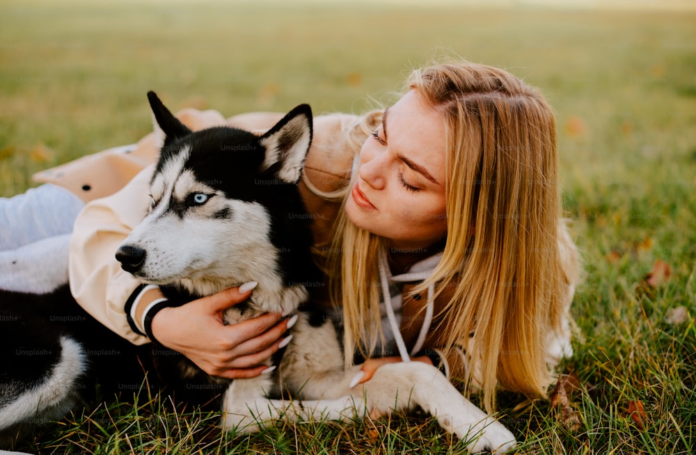 a woman laying on the grass with a husky dog