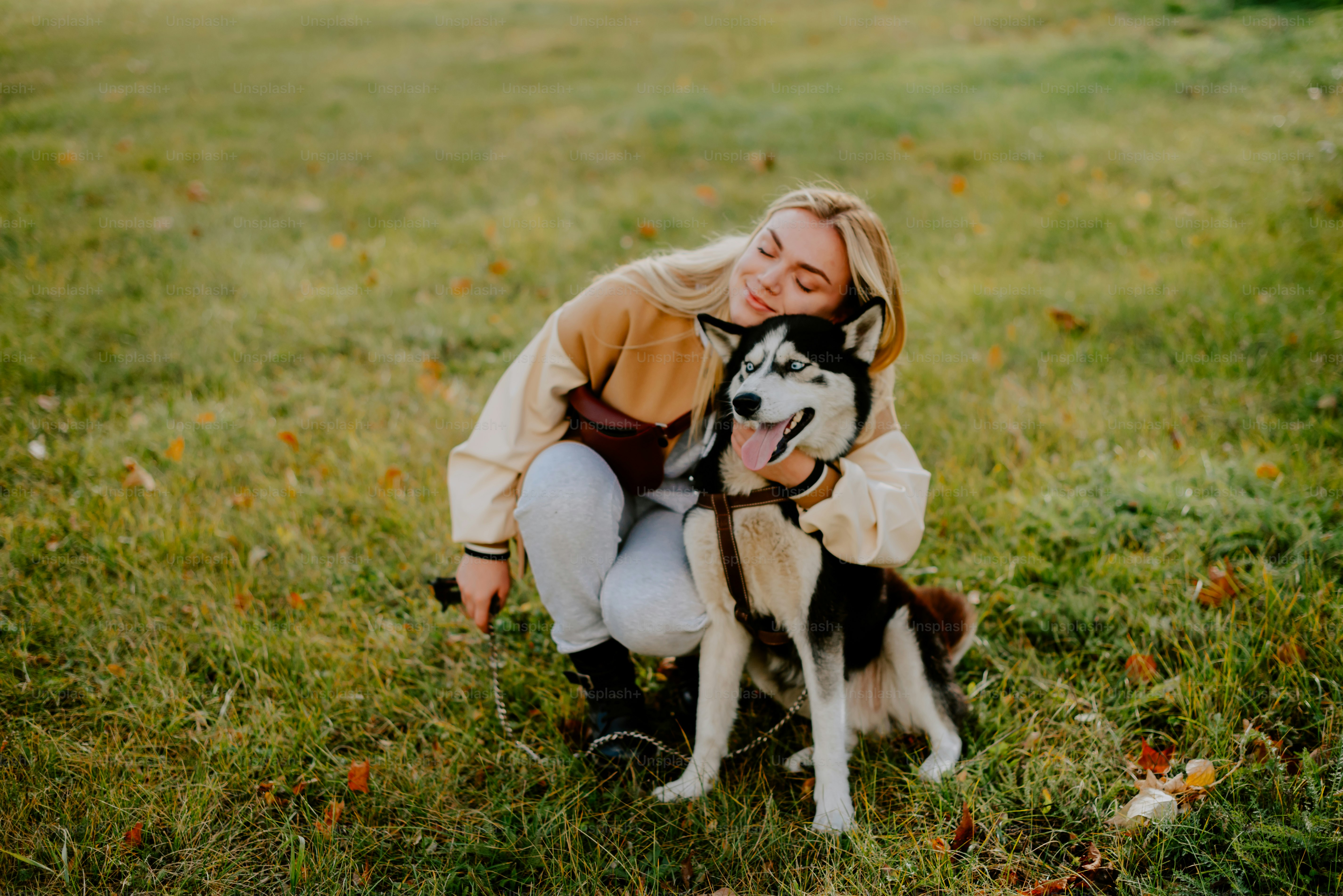 Una mujer abrazando a un perro husky en un campo