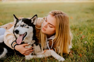 uma mulher deitada na grama com um cão husky