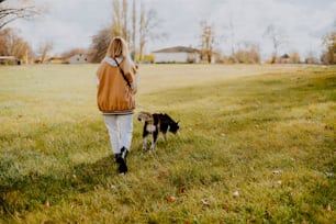 uma mulher passeando com um cachorro em uma coleira em um campo