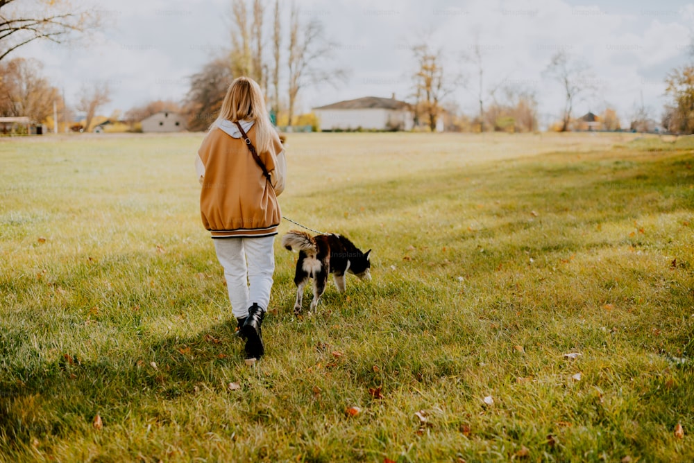 Une femme promenant un chien en laisse dans un champ