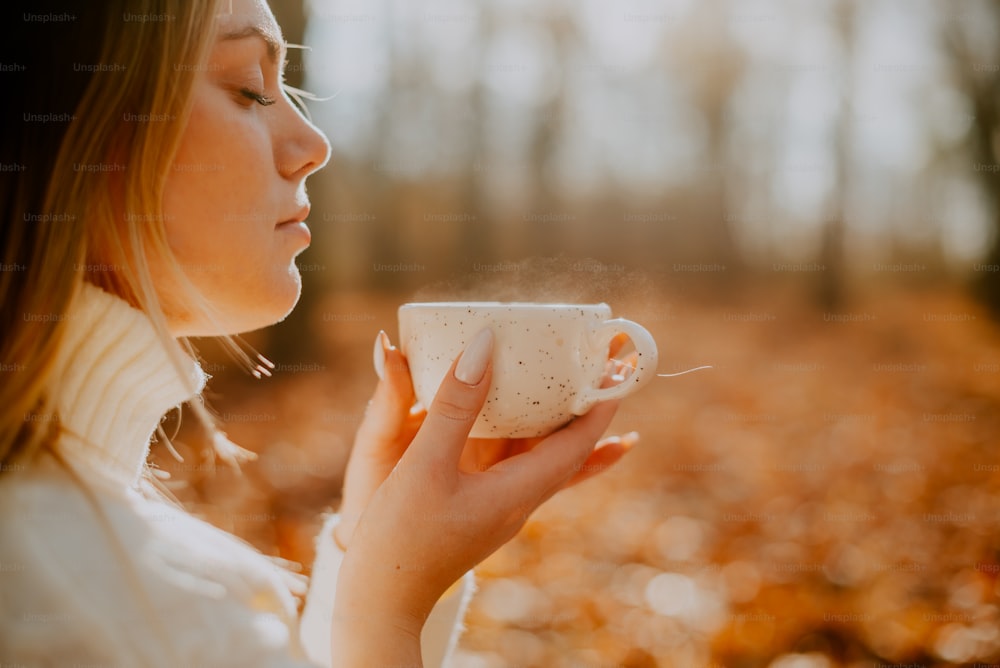 uma mulher segurando uma xícara de café nas mãos