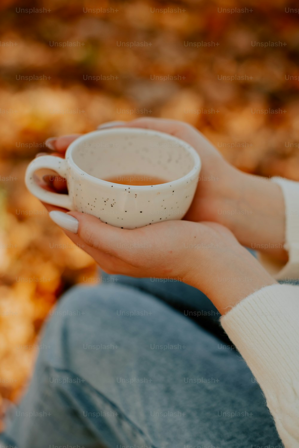 uma mulher segurando uma xícara de chá em suas mãos