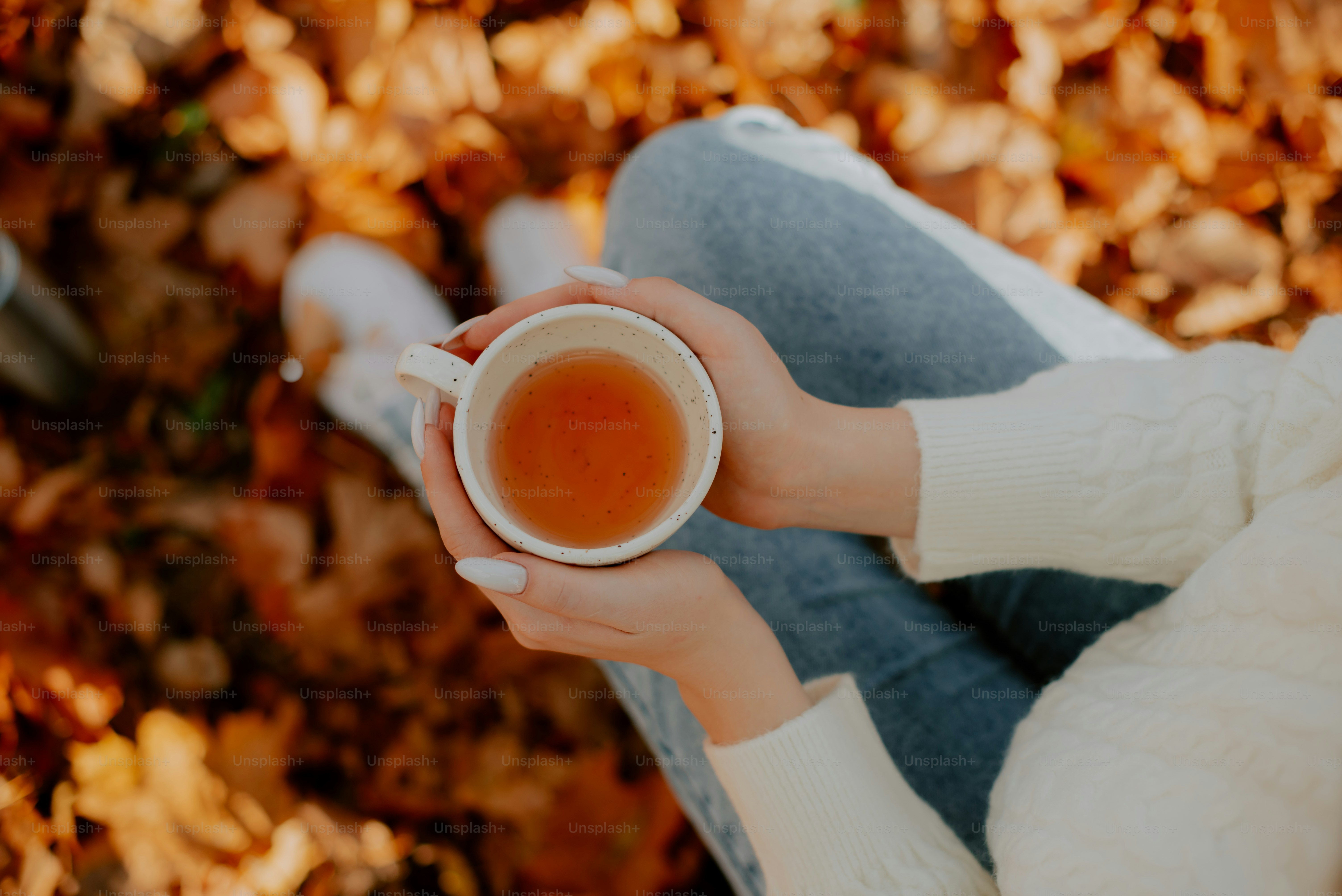 uma mulher segurando uma xícara de chá em suas mãos