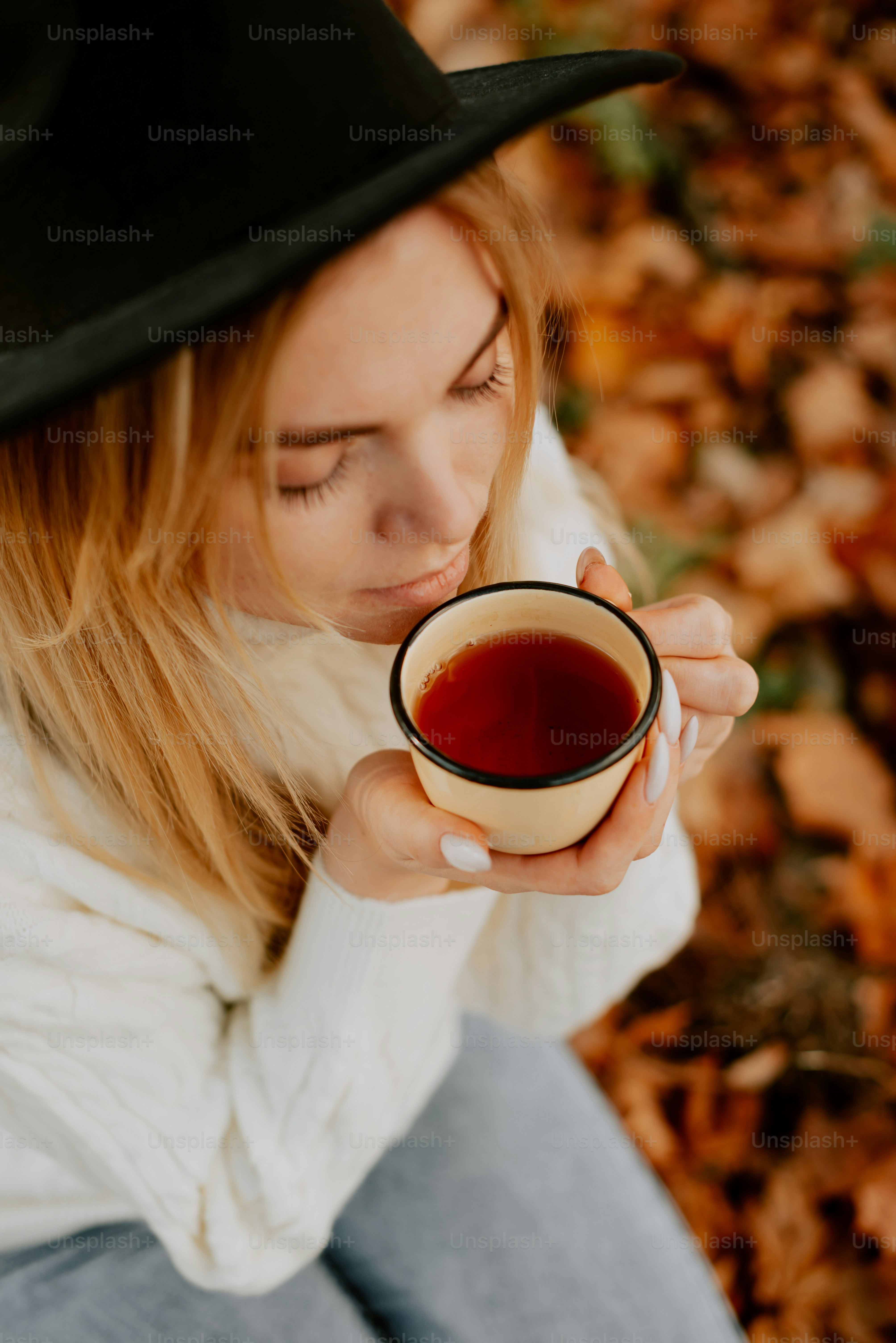 a woman in a black hat holding a cup of tea