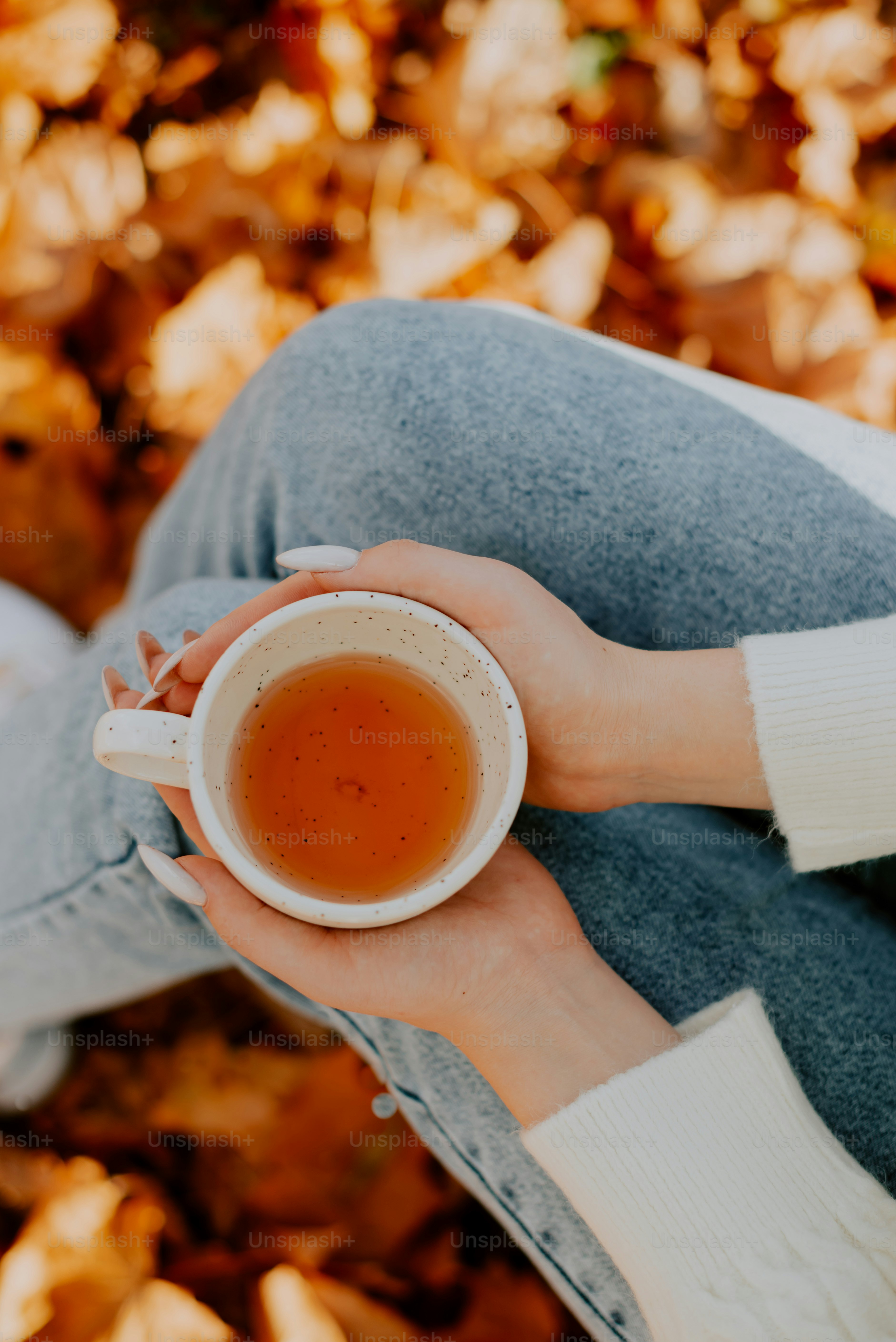 a woman holding a cup of tea in her hands