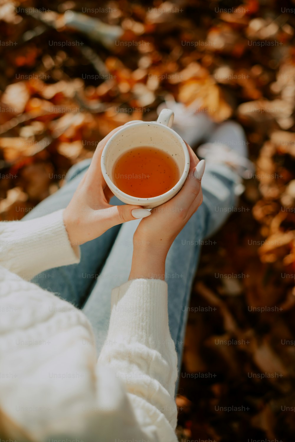 uma mulher segurando uma xícara de chá em suas mãos
