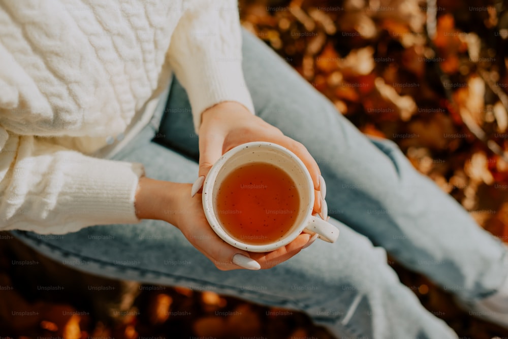 a woman holding a cup of tea in her hands