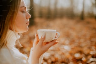 a woman holding a cup of coffee in a forest