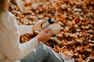 a woman sitting on the ground holding a cup of coffee