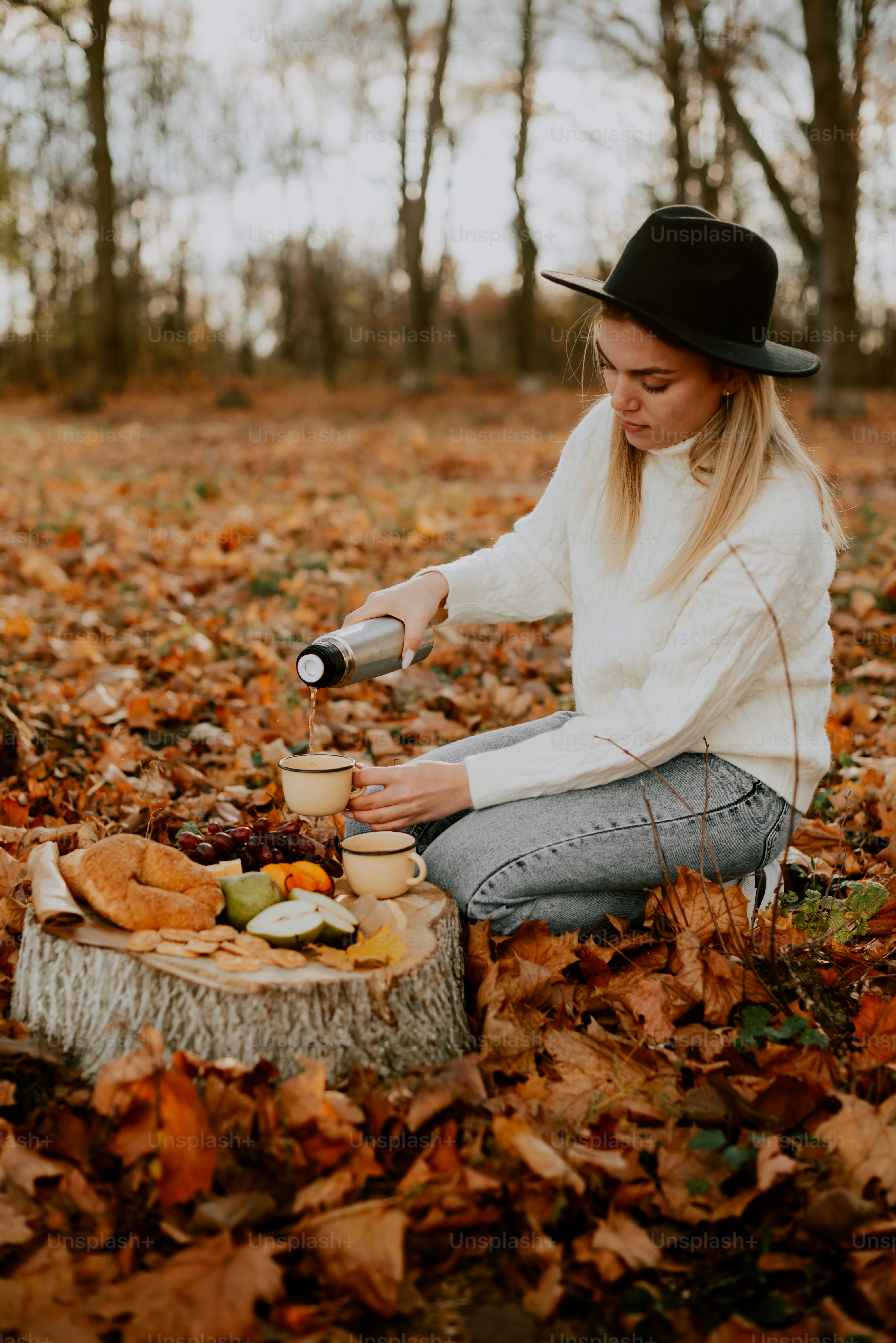 uma mulher sentada em um toco de árvore nas folhas