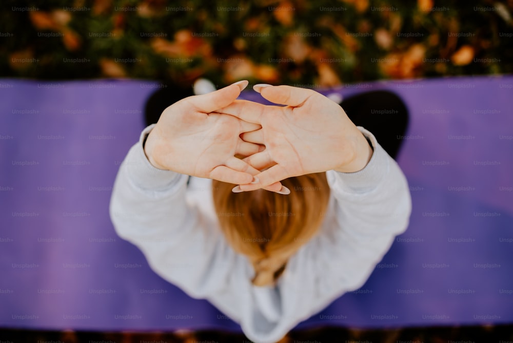 a woman sitting on a yoga mat holding her hands together