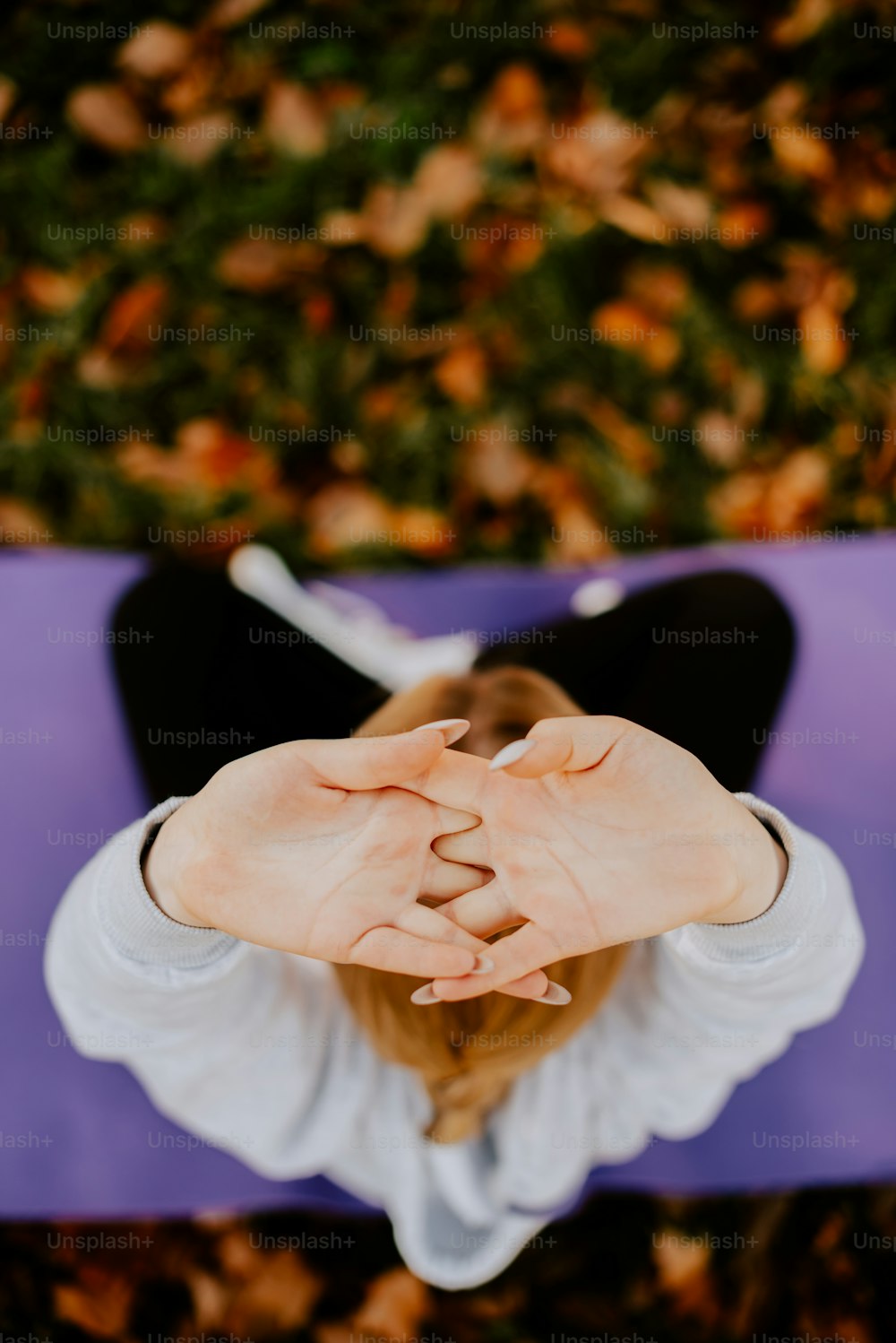 a woman sitting on a yoga mat holding her hands together