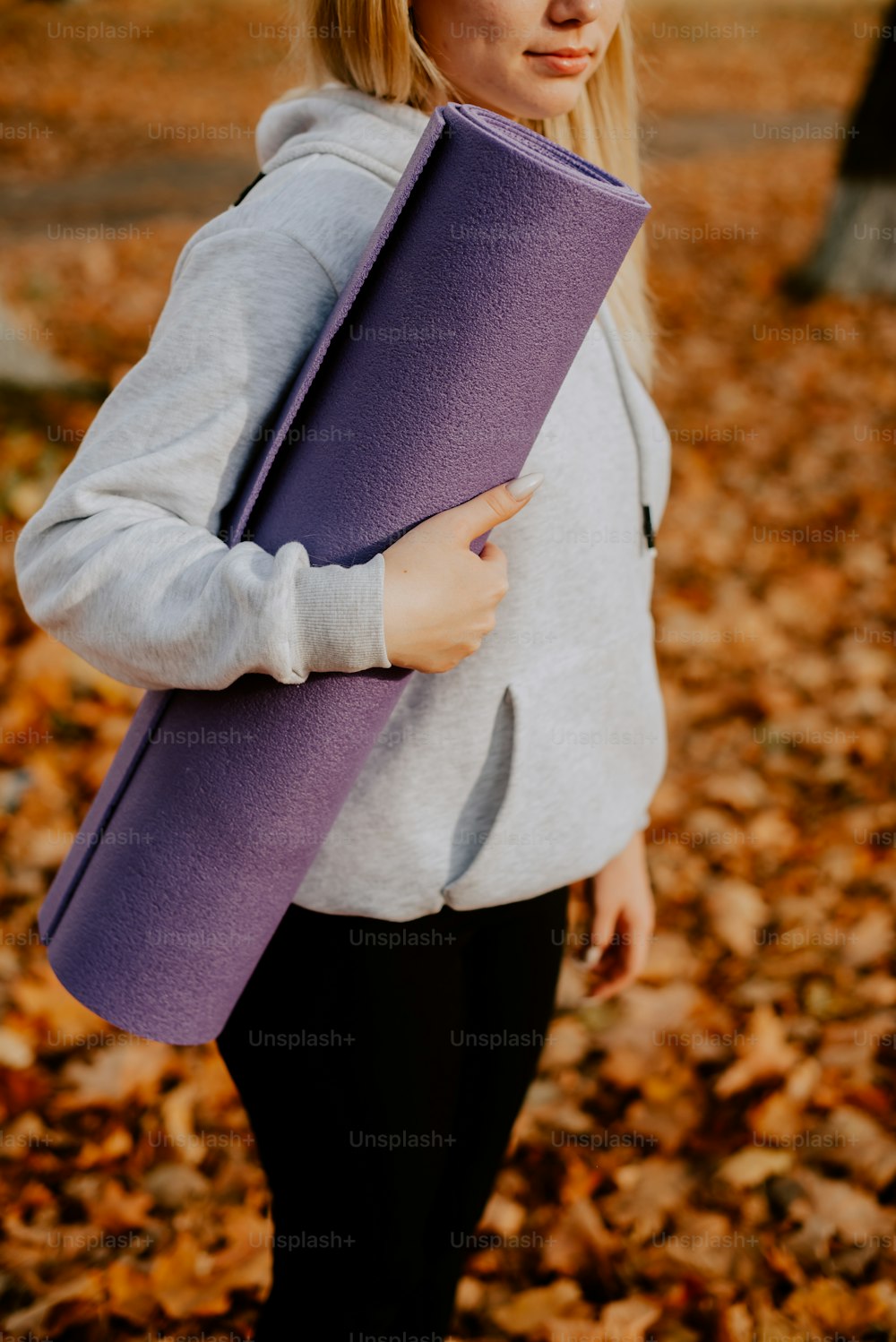 a woman holding a yoga mat in a park