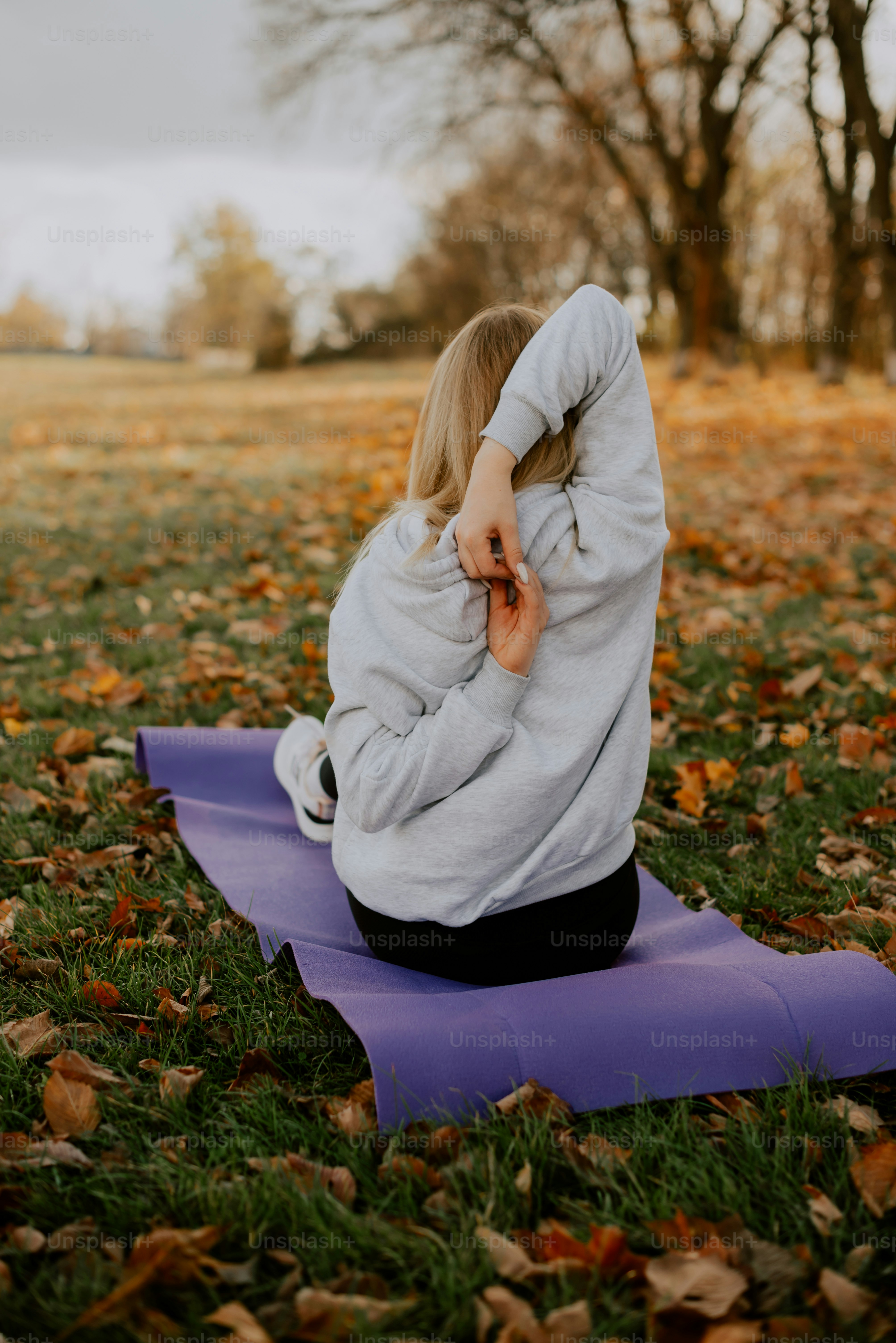 a woman sitting on a yoga mat in a park