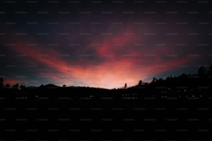 a red and blue sky with some trees in the background