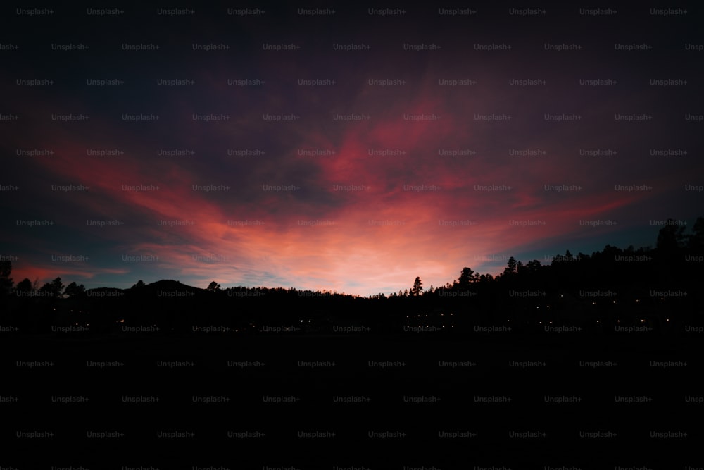 a red and blue sky with some trees in the background