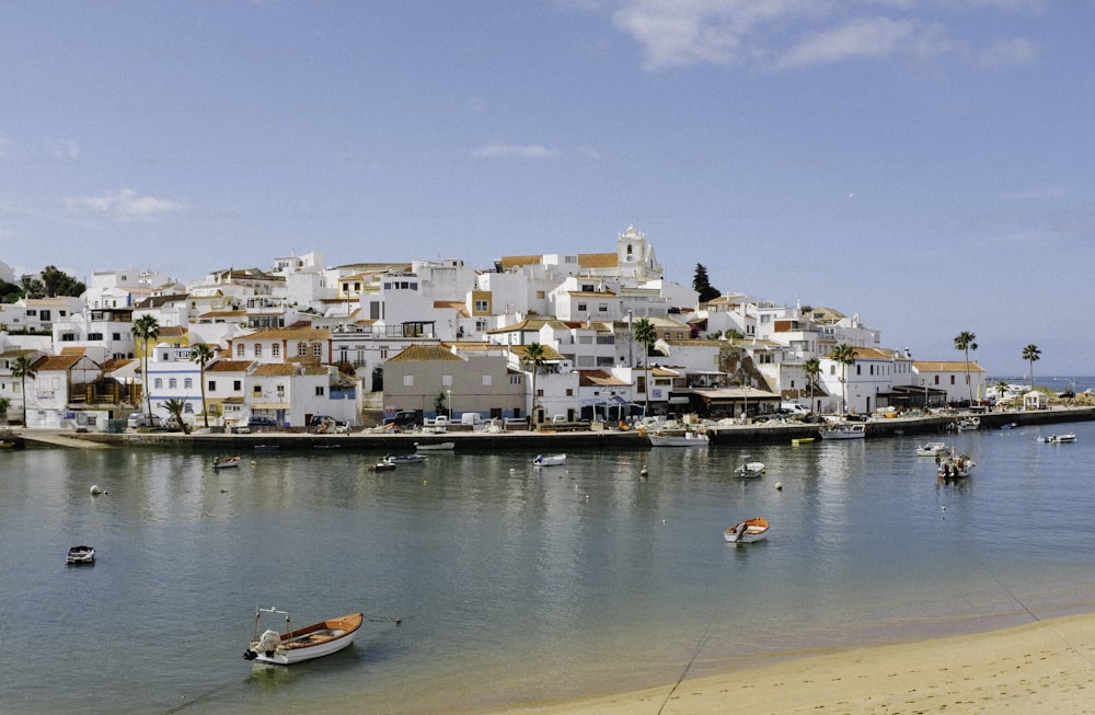 a beach with boats in the water and houses on a hill in the background