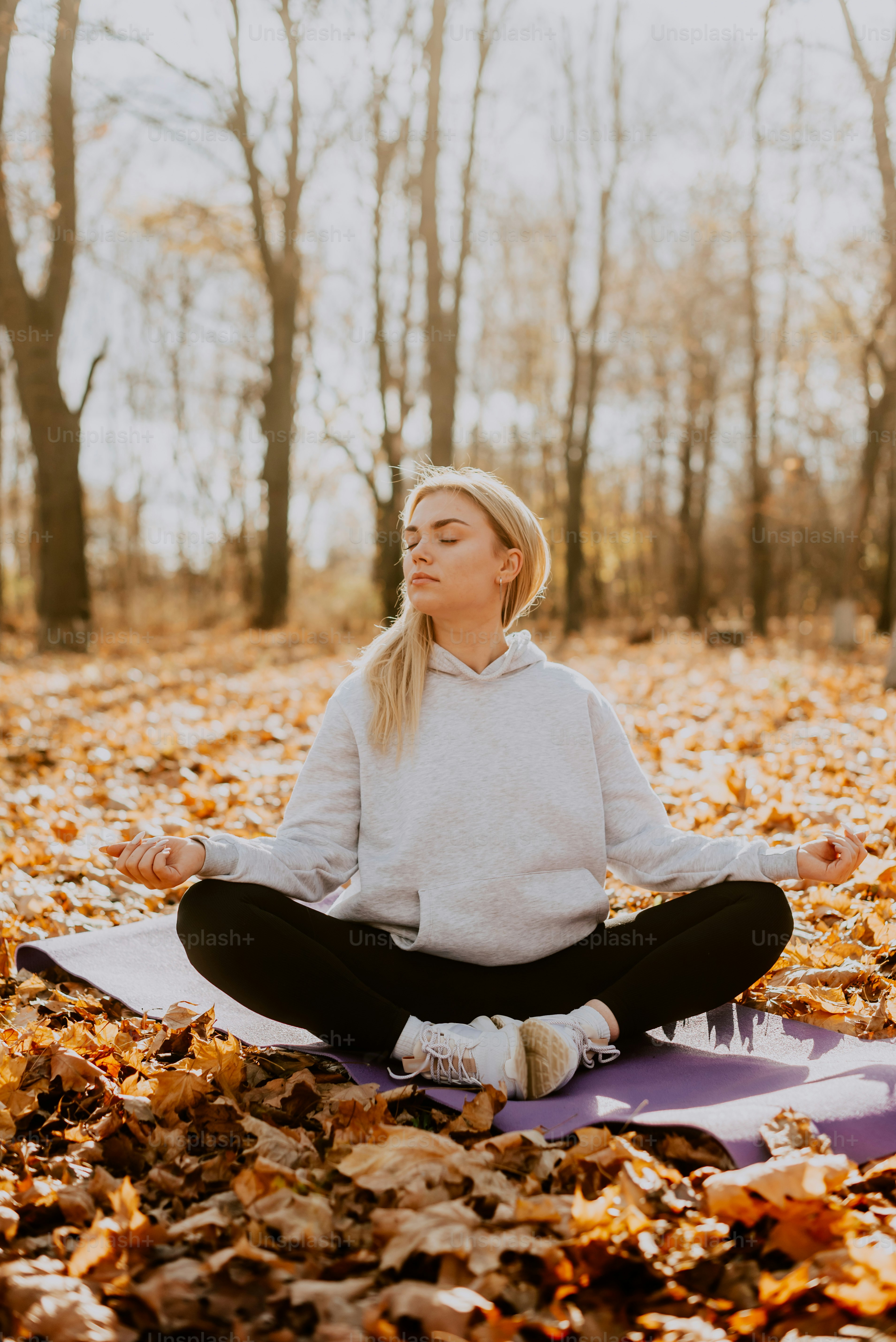 a woman is sitting in the middle of a leaf filled forest