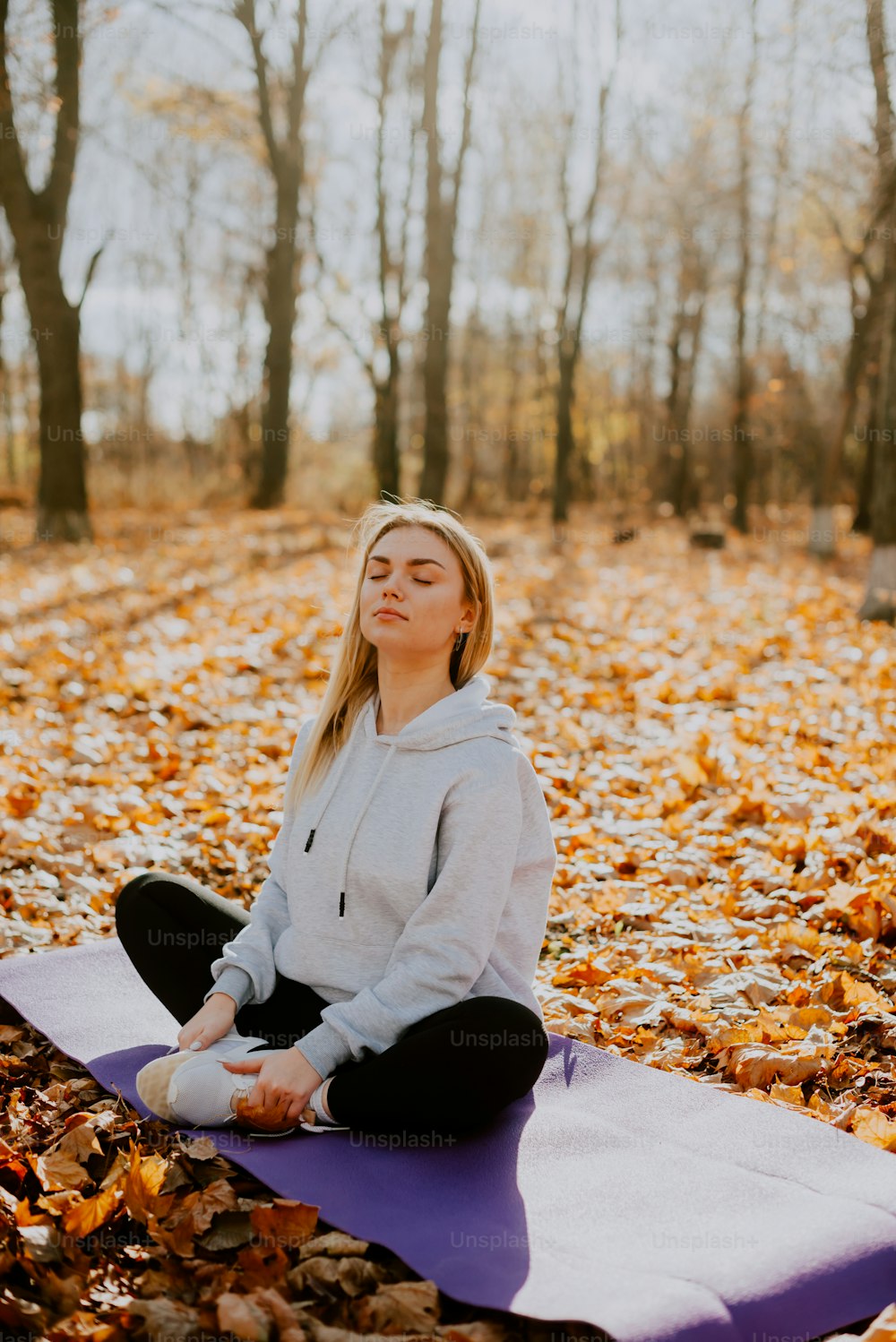 Una mujer sentada en una esterilla de yoga en el bosque