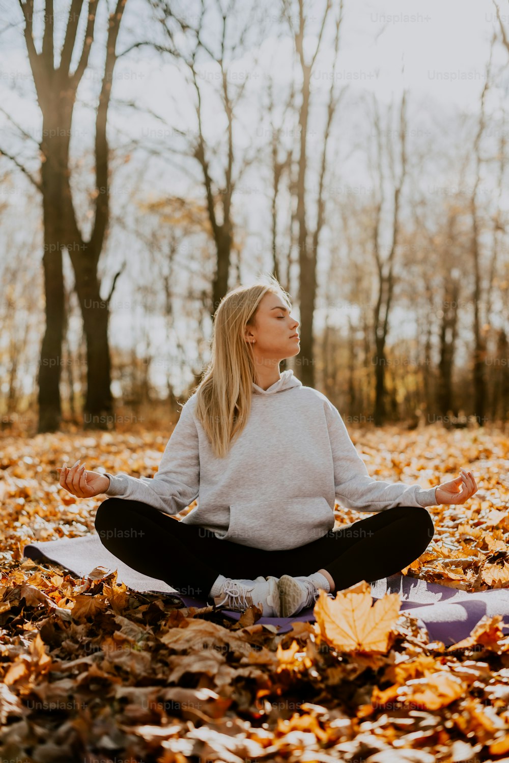 a woman is sitting in the middle of a leaf filled field