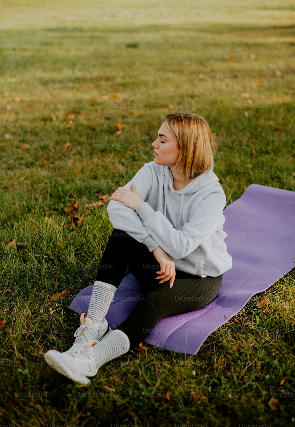 Una mujer sentada en una esterilla de yoga en la hierba