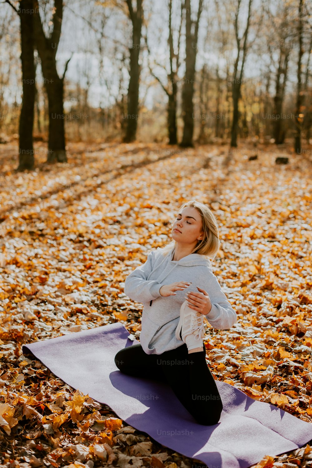 uma mulher sentada em um tapete de ioga na floresta