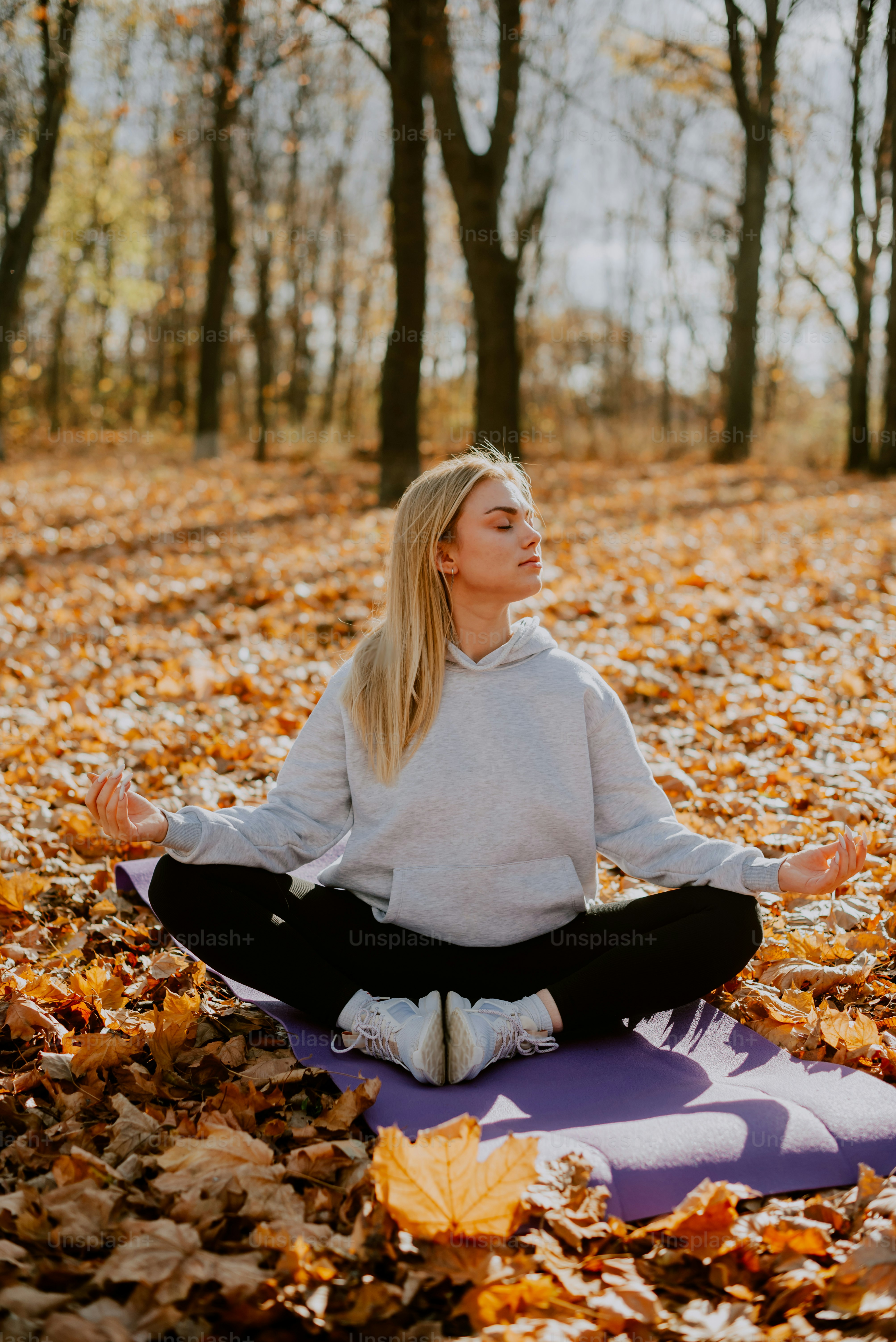 A woman sitting on a yoga mat in the woods photo – Fitness Image on ...