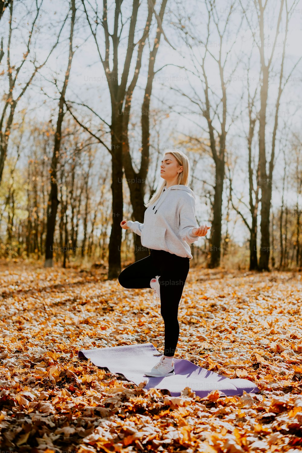a woman is doing yoga in the leaves
