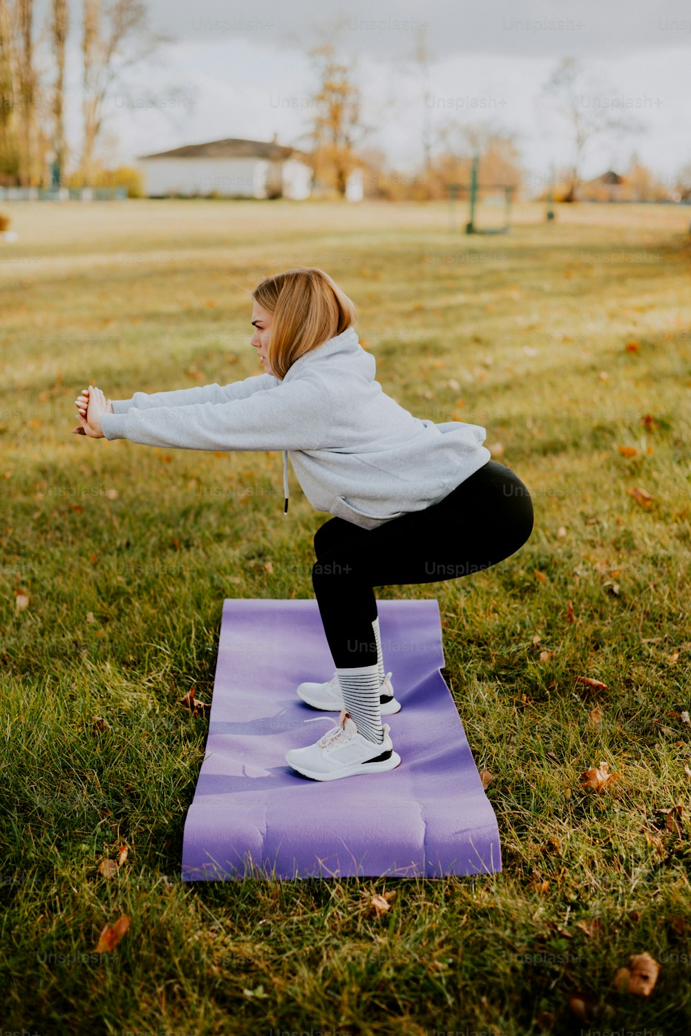 Una mujer haciendo una pose de yoga en una estera púrpura