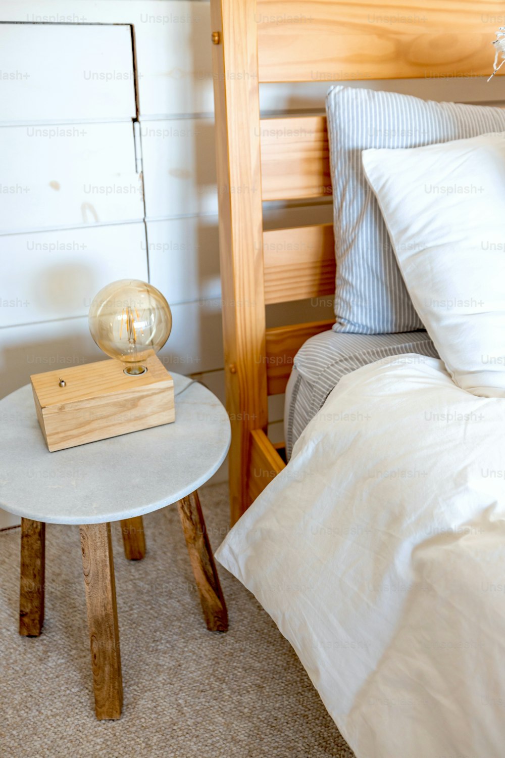 ein Bett mit einer weißen Bettdecke und einem hölzernen Nachttisch