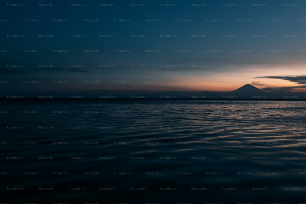 a large body of water with a mountain in the distance