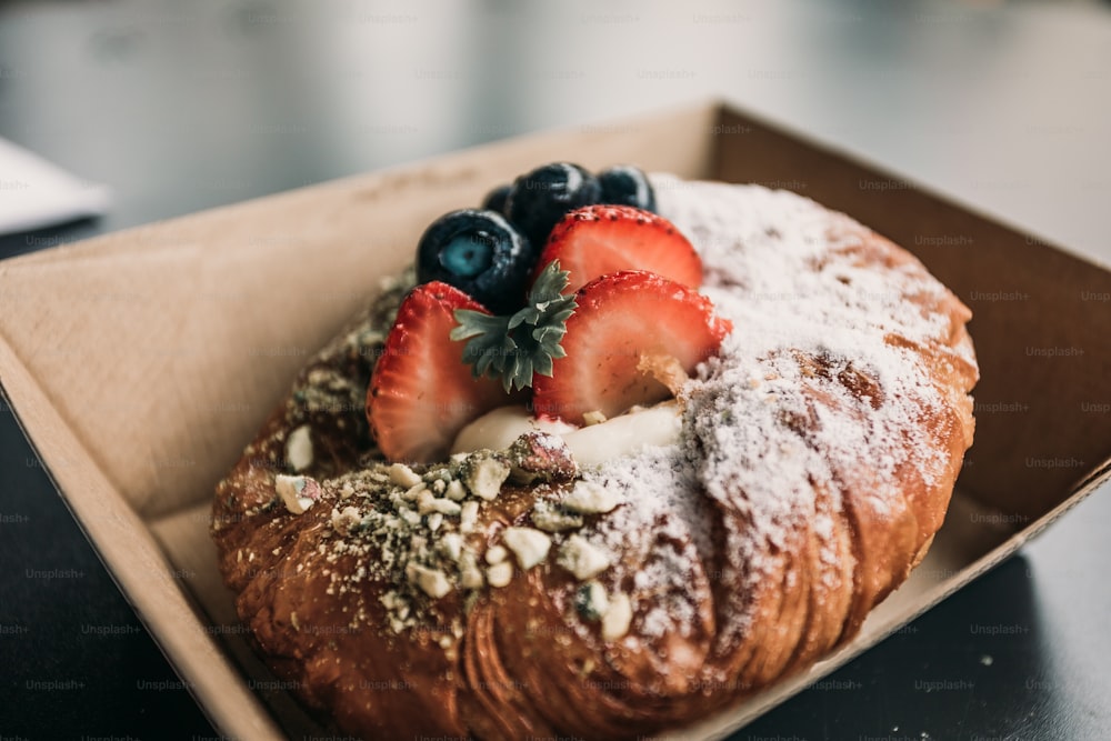 a pastry with powdered sugar and strawberries in a box