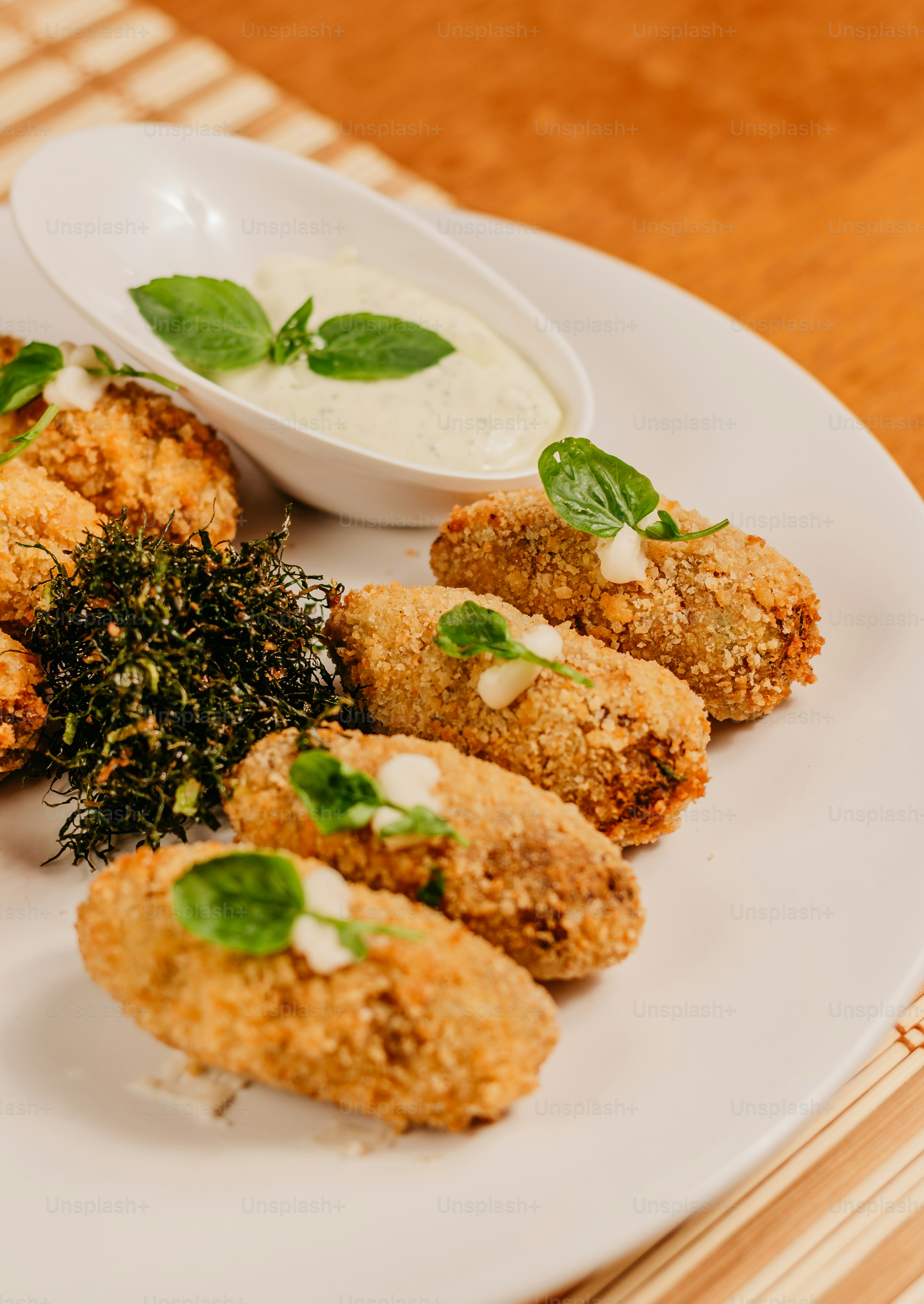 un piatto bianco sormontato da cibi fritti accanto a una ciotola di salsa