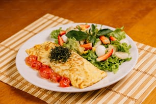 une assiette blanche garnie d’une omelette à côté d’une salade