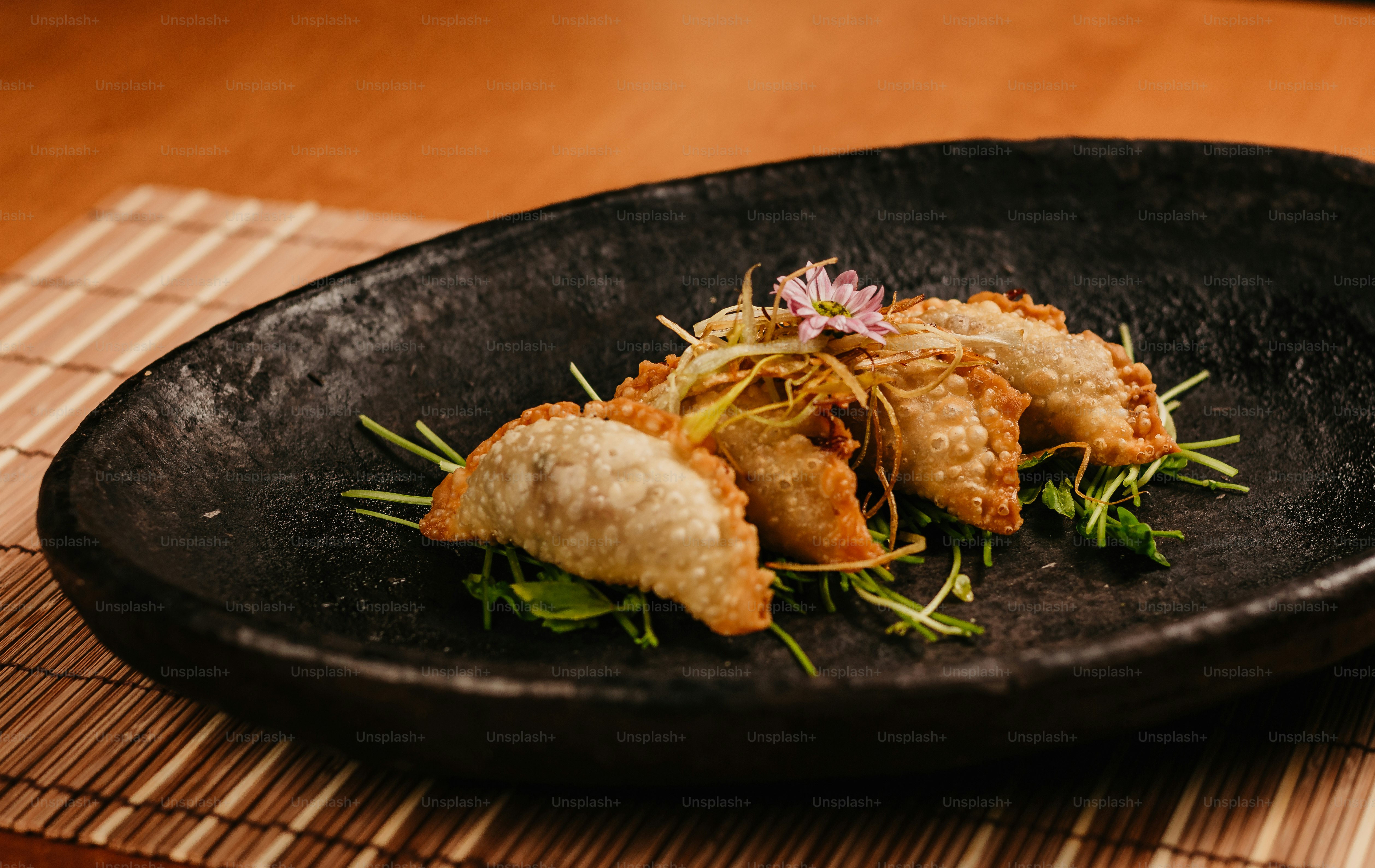 a black plate topped with fried food on top of a wooden table