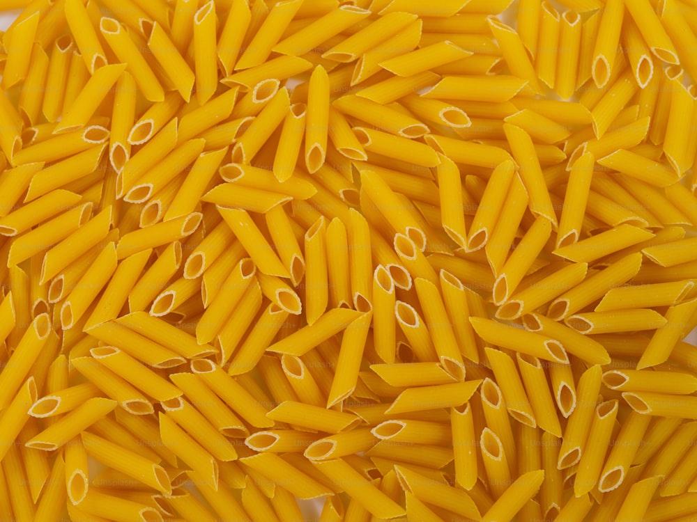 a pile of yellow pasta noodles on a white surface