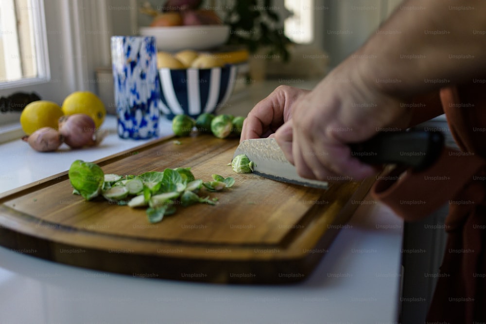 une personne qui coupe des légumes sur une planche à découper