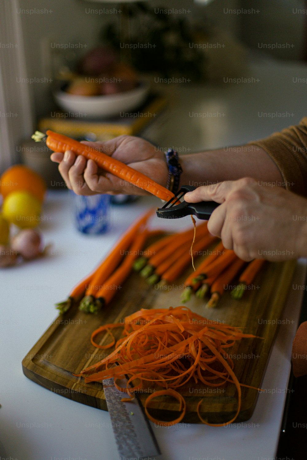 une personne coupant des carottes avec un couteau sur une planche à découper