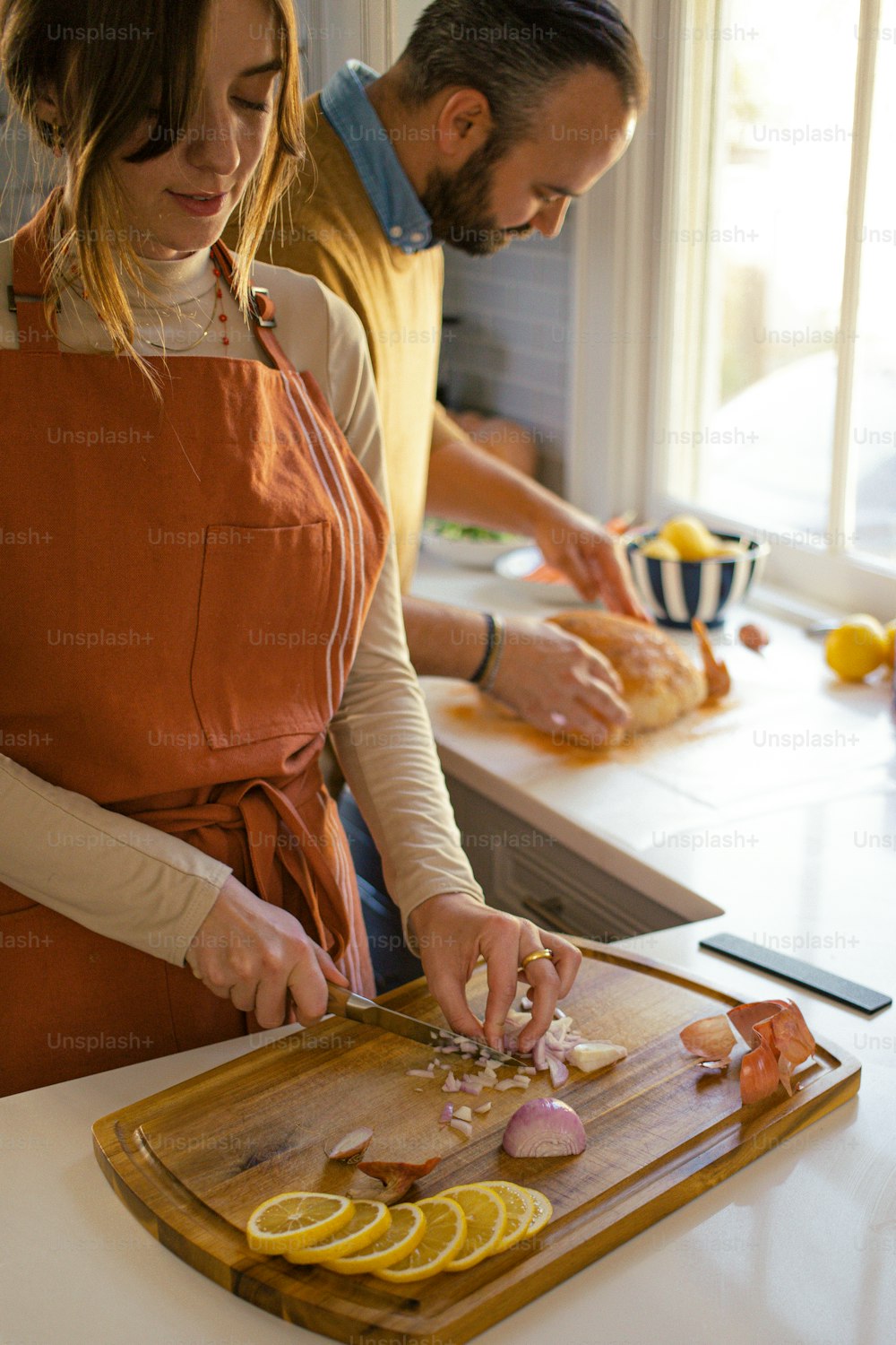 a man and a woman are preparing food on a cutting board